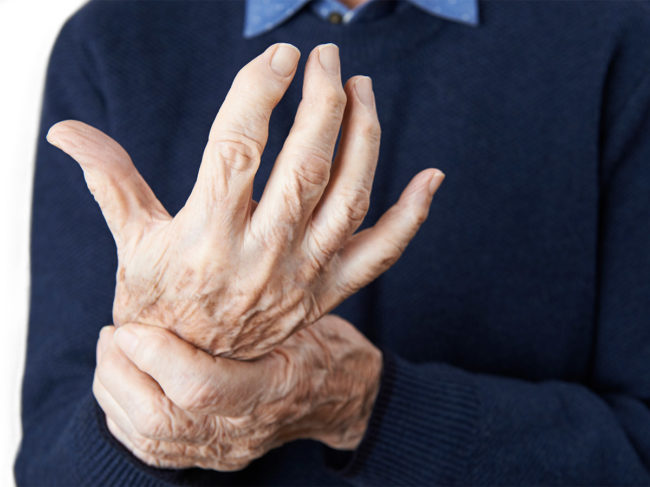 Close up of senior man holding wrist of arthritic hand